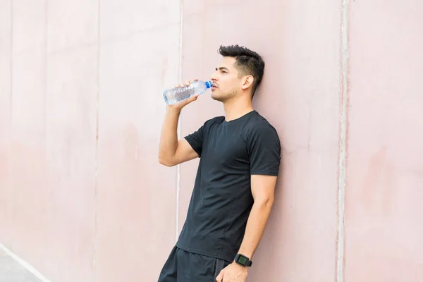 Nachdenklicher Erschöpfter Athlet Trinkt Wasser Während Sich Die Wand Lehnt — Stockfoto