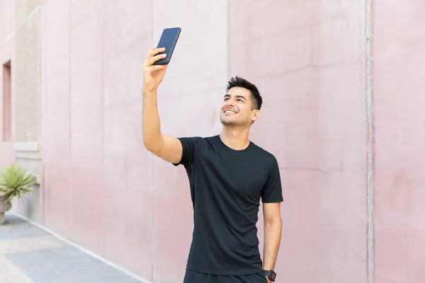 Smiling male jogger taking selfie after workout in city