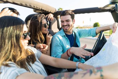 Yolculuk sırasında 4x4 araçta otururken konuşan neşeli arkadaşlar