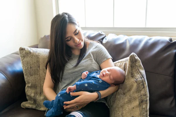 Latijnse Vrouw Die Zoon Draagt Terwijl Hij Thuis Bank Zit — Stockfoto