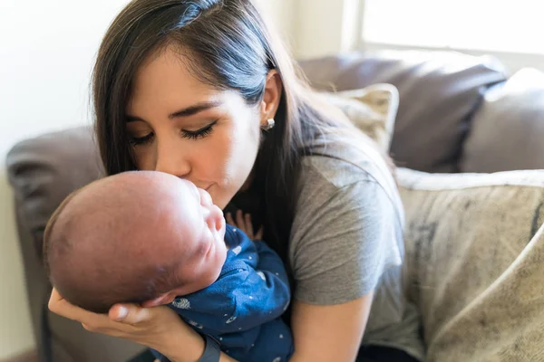 Madre Hispana Besando Bebé Recién Nacido Mientras Está Sentada Sofá — Foto de Stock