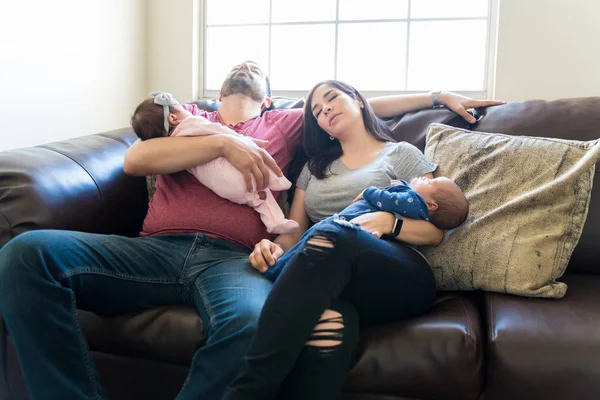 Виснажені Батьки Середнього Віку Носять Сплячих Немовлят Відпочивають Дивані — стокове фото