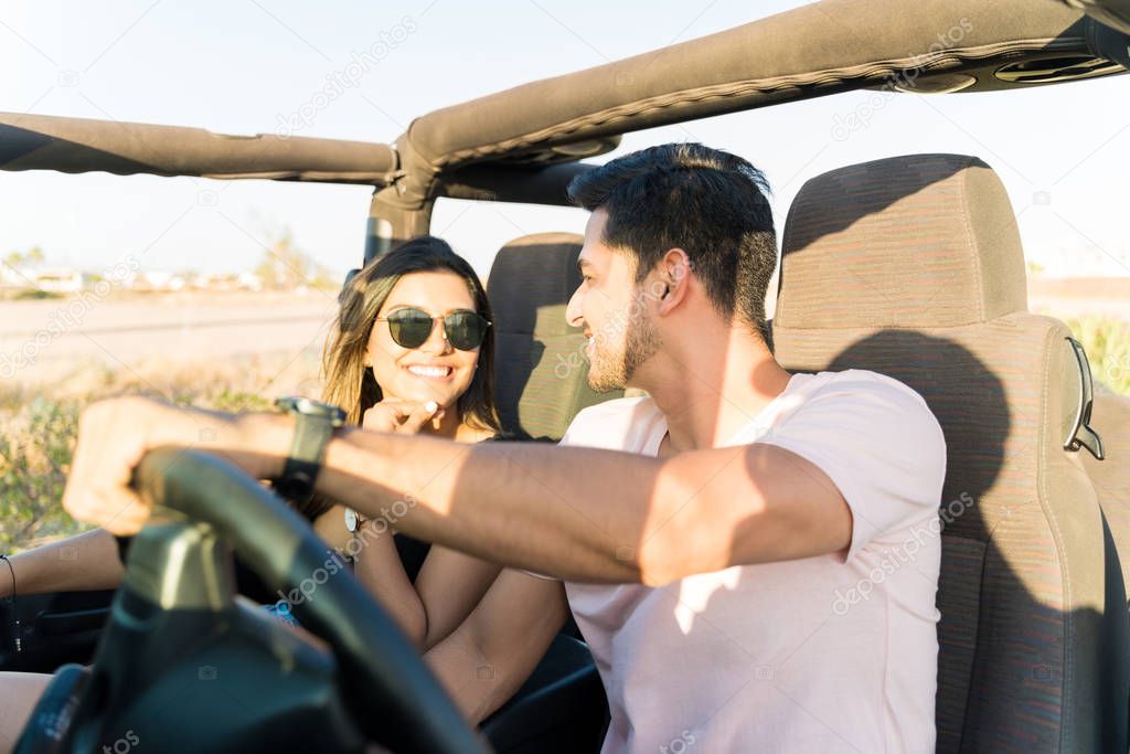 Latin couple talking while traveling in SUV on summer vacation