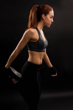 İzole arka plan karşı bakarken bacağını germe genç kadının yan görünümü