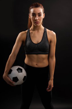 Siyah arka plan karşı topu tutan kendine güvenen genç kadın futbolcu portresi