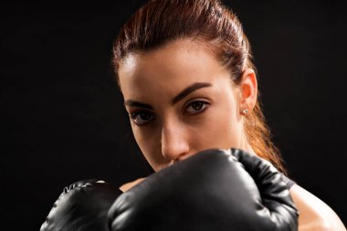 Siyah arka planda mücadele duruşunda emin kadın boksör yakın çekim portre