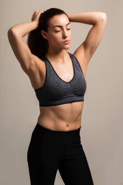 Kahverengi arka plan karşı egzersiz öncesi gözleri kapalı sıkma at kuyruğu ile Kafkas kadın atlet