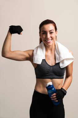 Renkli arka plan karşı pazı esneme sırasında su şişesi tutan gülümseyen kadın