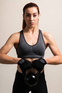 Düz arka plan karşı kettlebell ile kendine güvenen kadın atlet eğitim