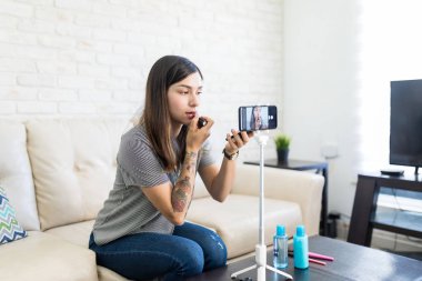 Vlogger evde makyaj öğretici video kaydederken ruj uygulayarak