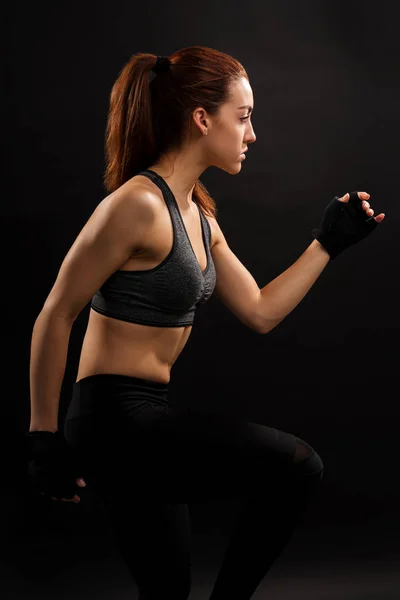 年轻女运动员在平淡背景下锻炼的侧视图 — 图库照片