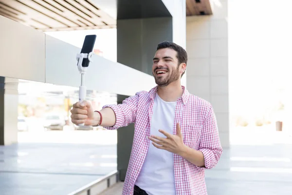 Happy blogger recording live video on smartphone at shopping mall