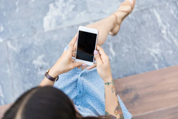 坐在购物中心时使用智能手机的女性博主的高角度视图 — 图库照片