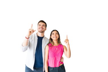 Gülümseyen İspanyol erkek arkadaşı ve kız arkadaşı stüdyoda kopya alanı doğru bakarken gesturing