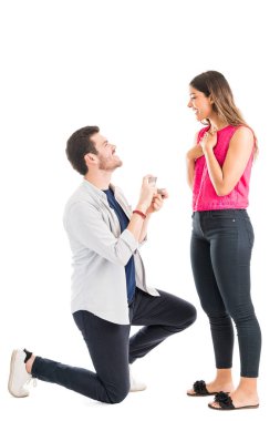 Genç adam kız arkadaşı önünde diz çökmüş ve beyaz arka plan karşı halka ile bir teklif yapma tam uzunlukta