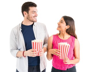 Sevgi dolu İspanyol kız arkadaşı ve erkek arkadaşı stüdyoda birbirlerine bakarken patlamış mısır tutan