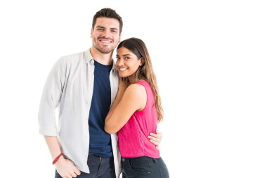 Beyaz arka plana karşı birlikte duran gülümseyen şık çiftin portresi