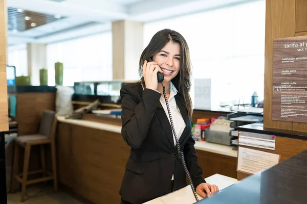 ホテルのロビーで目を合わせながら電話に出る幸せな女性ホテル店員 — ストック写真