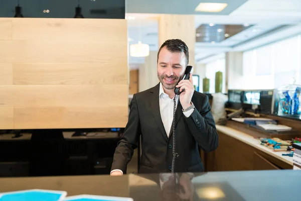 Glückliche Männliche Empfangsdame Bestätigt Buchung Während Sie Telefonisch Der Rezeption — Stockfoto