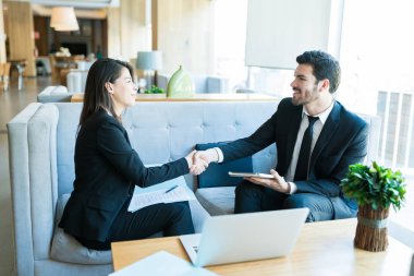Gülümseyen iş uzmanları lobide toplantı sırasında el sıkışması ile tebrik