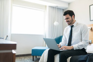 Otel odasında yatakta otururken laptop üzerinde çalışan çekici Ispanyol girişimci