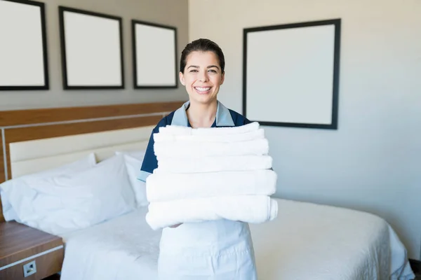 ホテルの部屋に立っている間 きれいなタオルのスタックを保持する魅力的な幸せなラテンメイド — ストック写真