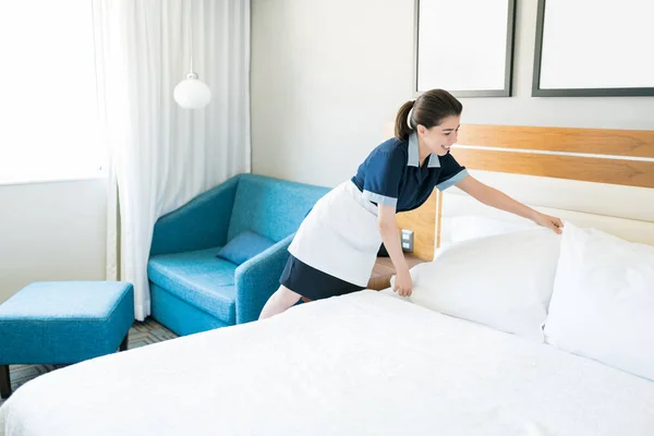 Sorridente Cameriera Uniforme Organizzare Cuscini Sul Letto Camera Albergo — Foto Stock