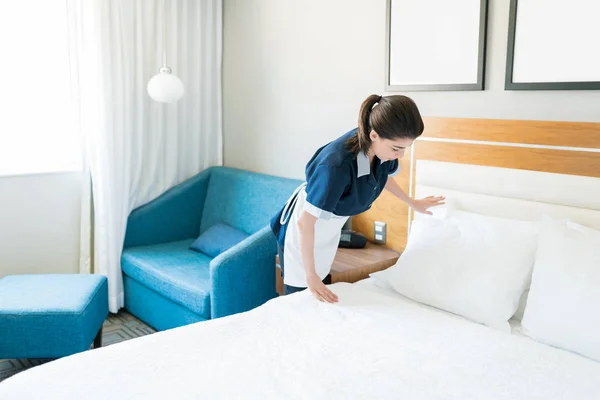 ミッド大人の室内メイドは ホテルの部屋のベッドに枕を置きます — ストック写真