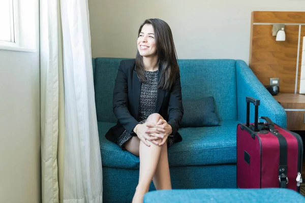 Thoughtful Smiling Latin Executive Sitting Sofa Suitcase While Looking Window — Stock Photo, Image