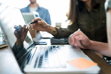 Profesyoneller işyerinde toplantıda dizüstü bilgisayar üzerinden proje tartışıyor