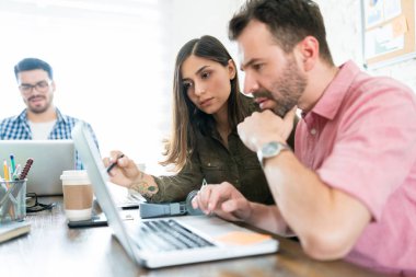 Ofis masasında laptop üzerinden erkek ve kadın meslektaşları planlama stratejisi