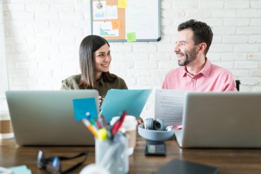 Gülümseyen iş arkadaşları çalışma alanında toplantı sırasında belgeler üzerinde planlama