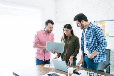 Yöneticiler ofis toplantısında meslektaşları ile dizüstü iş planı üzerinde tartışıyor