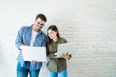 İşyerinde beyaz duvara ayakta iken dizüstü bilgisayarlarda çalışan profesyonel iş ortakları