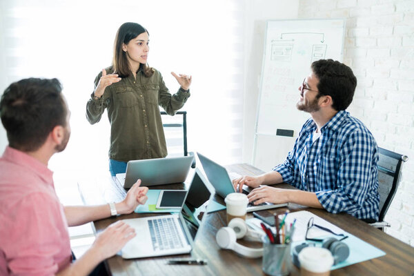 Professional leader sharing ideas with coworkers during business meeting in office