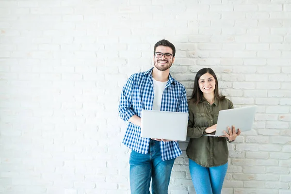 Profesionales Masculinos Femeninos Confiados Sosteniendo Computadoras Portátiles Contra Pared Blanca —  Fotos de Stock