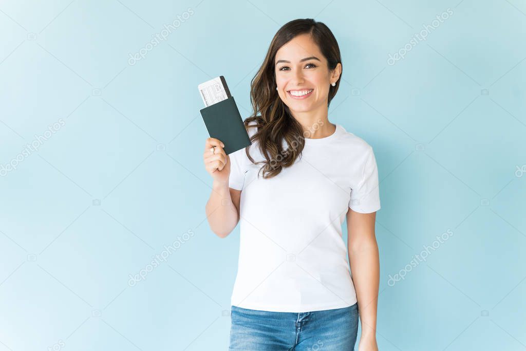 Happy pretty female tourist with passport isolated on colored background