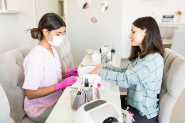 Manikürcü güzellik salonunda kase de el yıkama kadın müşteri bakıyor