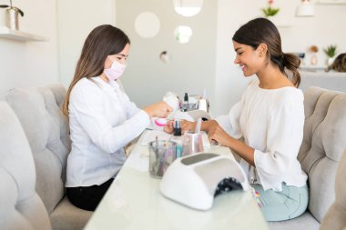 Kadın kozmetik salonunda müşteri tırnakları gülümseyen üzerinde çalışıyor