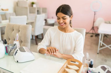 Spa'da tedavi sonrası manikürlü tırnakları bakarak memnun kadın müşteri