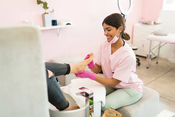 Smiling Latin Pedikuris Memberikan Pijat Kaki Kepada Pelanggan Salon Kecantikan — Stok Foto