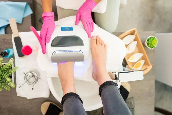 Pedicurista Asistiendo Cliente Uso Lámpara Ultravioleta Después Del Tratamiento Salón —  Fotos de Stock