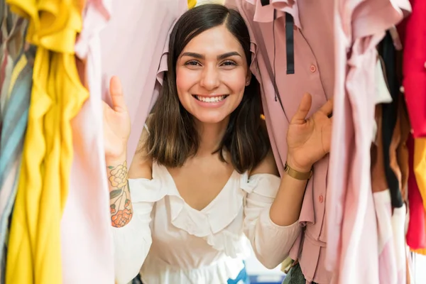 Beautiful Hispanic Woman Enjoying Shopping While Peeking Clothes Hanging Store — Stock Photo, Image