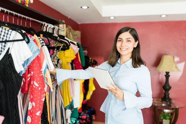 Latin Female Manager Holding Tablet While Standing Clothes Rack While — Stock Photo, Image