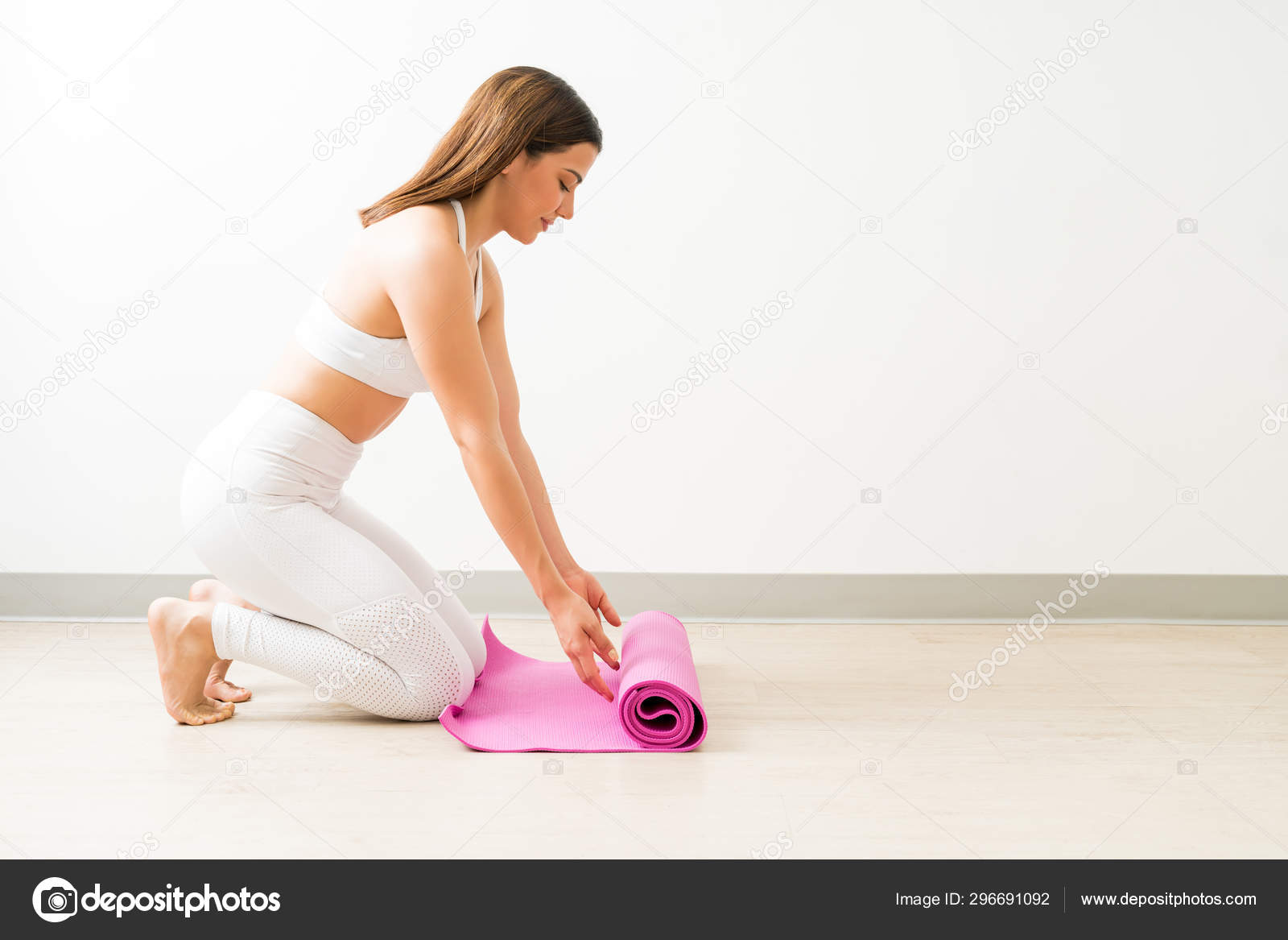 Attractive Caucasian Female Unrolling Pink Exercise Mat Hardwood