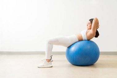 Egzersiz stüdyosunda parke zemin üzerinde karın kas egzersiz yapıyor genç kadın tam uzunlukta