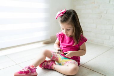 Evde yerde otururken pliers ile oynayan sevimli küçük çocuk