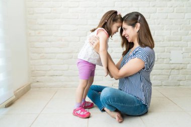 Gülümseyen anne ve kızı evde oturma odasında eğleniyor