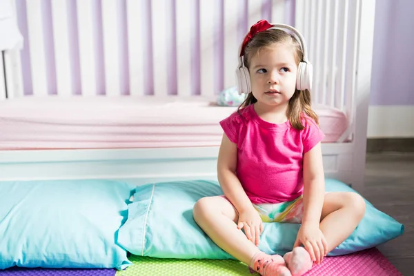 Śliczne Małe Dziecko Nosi Słuchawki Słuchania Muzyki Siedząc Poduszce Sypialni — Zdjęcie stockowe