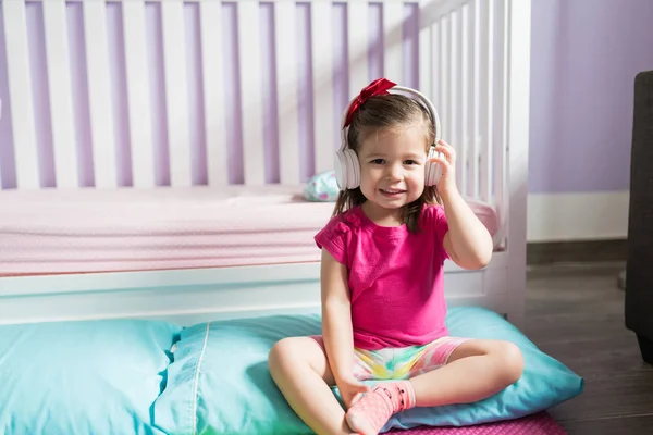 自宅で寝室でリラックスしながら ヘッドフォンで音楽を聴く笑顔の女性の幼児 — ストック写真